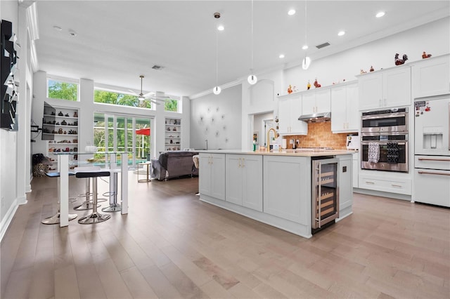 kitchen with visible vents, wine cooler, ceiling fan, under cabinet range hood, and high end refrigerator