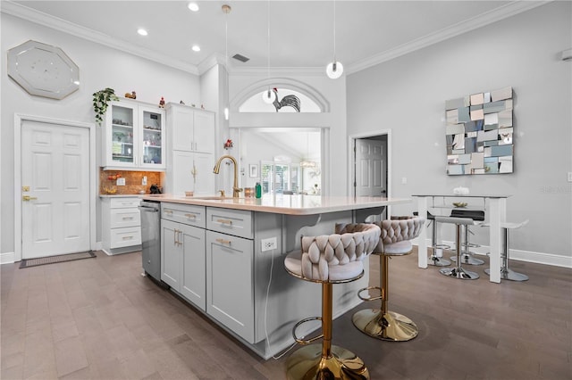 kitchen with crown molding, a sink, a kitchen island with sink, and light countertops