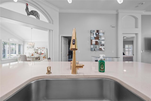 interior details featuring ornamental molding, light stone countertops, a chandelier, a sink, and decorative light fixtures