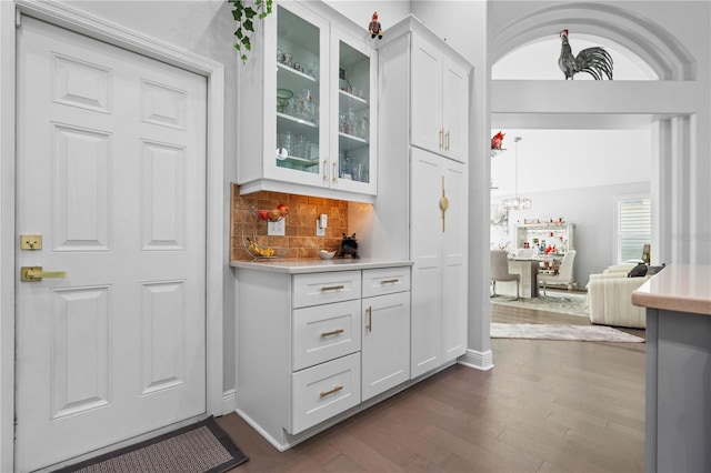 bar featuring indoor wet bar, dark wood finished floors, baseboards, and tasteful backsplash