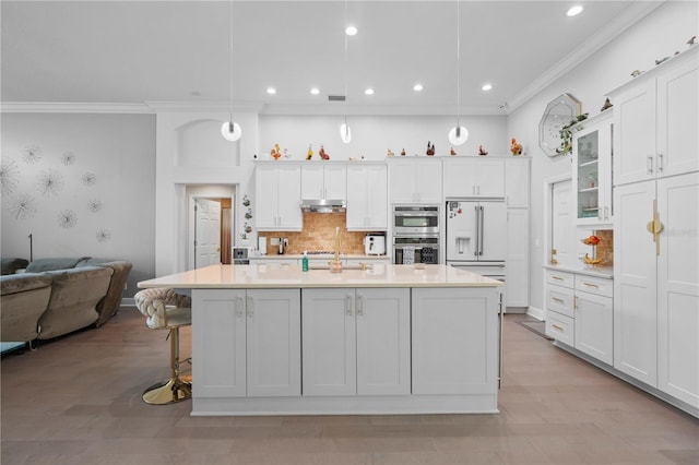 kitchen with double oven, recessed lighting, white cabinetry, under cabinet range hood, and ornamental molding
