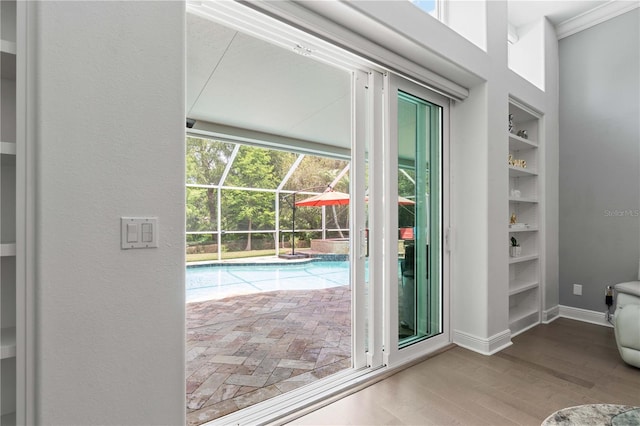 doorway with baseboards, ornamental molding, and wood finished floors