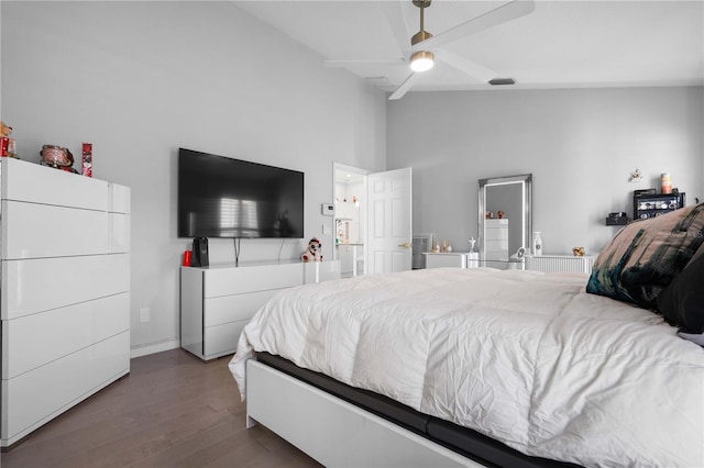 bedroom featuring a ceiling fan, visible vents, wood finished floors, and a towering ceiling
