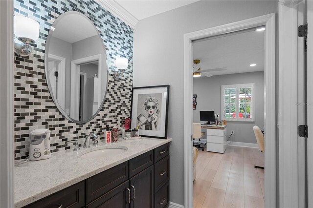 bathroom featuring vanity, decorative backsplash, wood finished floors, baseboards, and a ceiling fan