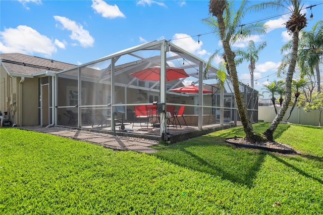 rear view of property featuring glass enclosure, fence, a yard, a patio, and stucco siding