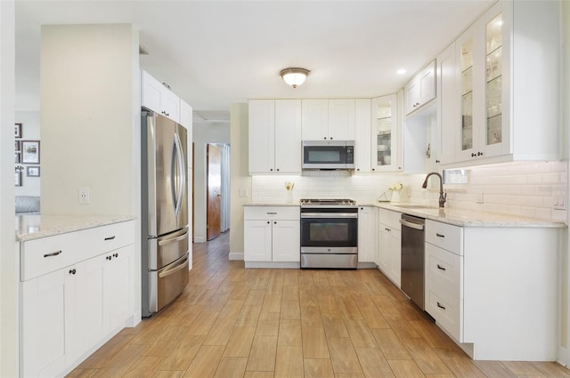 kitchen featuring white cabinets, a sink, stainless steel appliances, and decorative backsplash