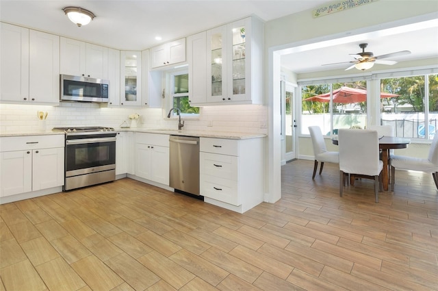 kitchen with white cabinetry, a sink, backsplash, and appliances with stainless steel finishes