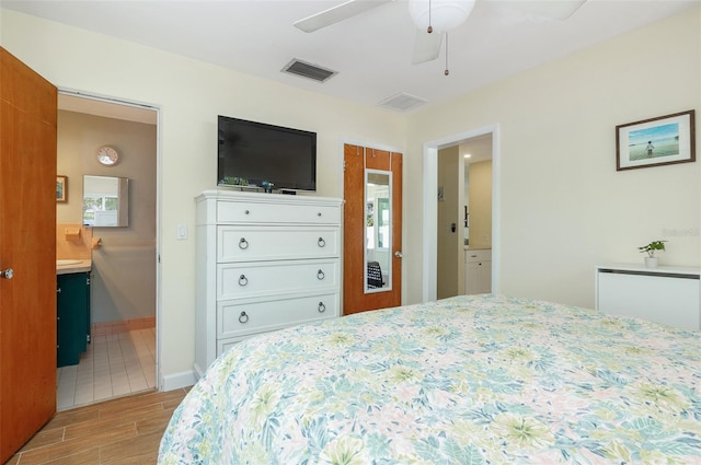 bedroom featuring light wood-style flooring, connected bathroom, baseboards, and visible vents