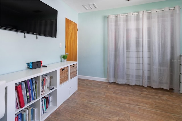 interior space featuring wood tiled floor, visible vents, and baseboards