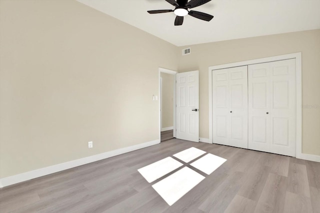 unfurnished bedroom featuring light wood-style flooring, a closet, baseboards, and visible vents
