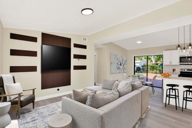 living room with visible vents, baseboards, recessed lighting, and light wood-style floors