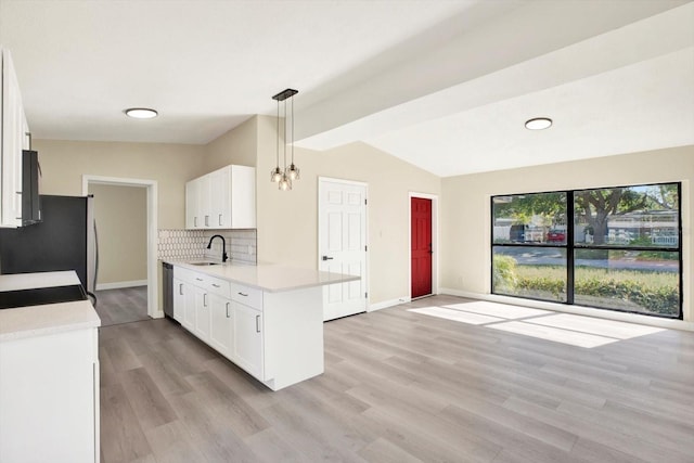 kitchen with lofted ceiling, a sink, light countertops, appliances with stainless steel finishes, and decorative backsplash