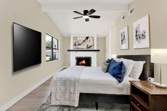 bedroom with visible vents, baseboards, vaulted ceiling with beams, and wood finished floors