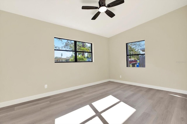 unfurnished room with wood finished floors, ceiling fan, baseboards, and a wealth of natural light