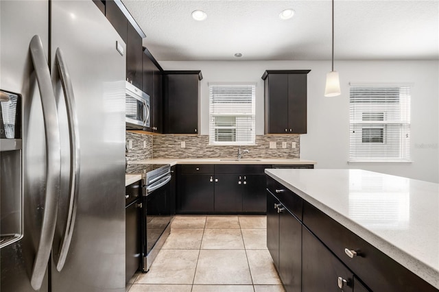 kitchen featuring light tile patterned floors, light countertops, appliances with stainless steel finishes, and decorative backsplash