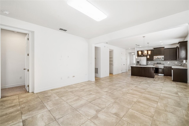 unfurnished living room with visible vents, baseboards, light tile patterned floors, a sink, and a chandelier