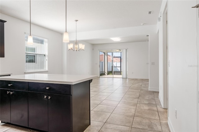 kitchen with visible vents, light tile patterned flooring, light countertops, dark cabinetry, and a notable chandelier