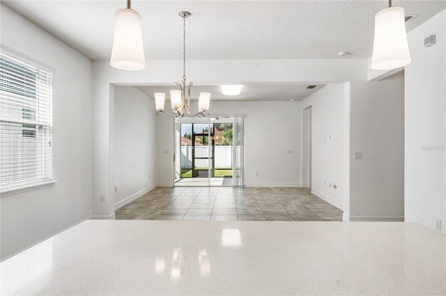 empty room featuring a chandelier and baseboards