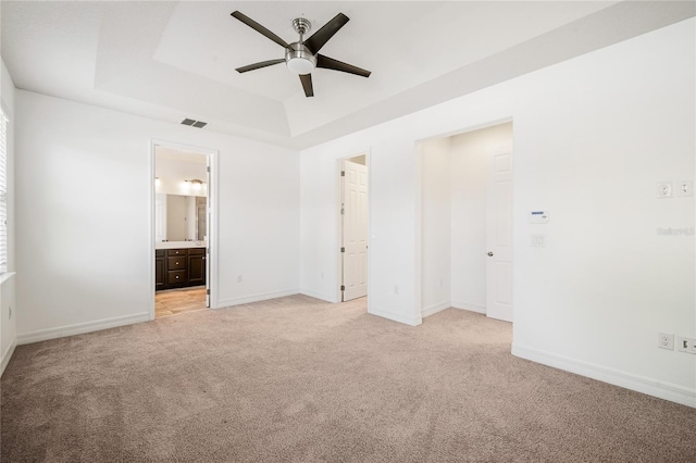 unfurnished bedroom with a raised ceiling, light carpet, baseboards, and visible vents
