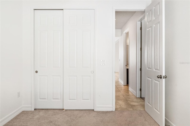 unfurnished bedroom featuring a closet, light colored carpet, and baseboards