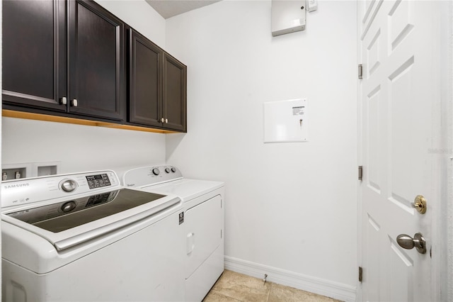 clothes washing area featuring light tile patterned floors, washer and clothes dryer, baseboards, and cabinet space