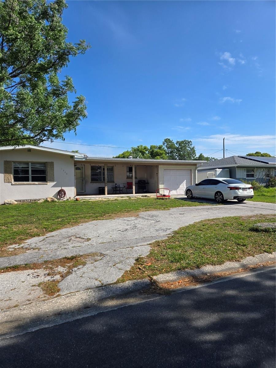 view of front facade featuring driveway, an attached garage, a front yard, and a porch