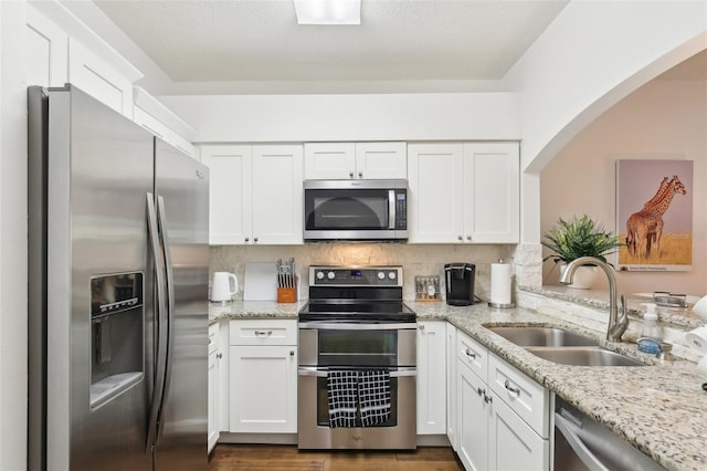 18187 Paradise Point Dr, Tampa, FL 33647 - kitchen featuring appliances with stainless steel finishes, a sink, white cabinetry, and arched walkways
