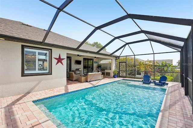 outdoor pool with outdoor lounge area, glass enclosure, ceiling fan, and a patio area