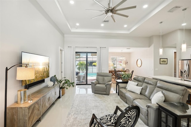 living area featuring a raised ceiling, recessed lighting, ceiling fan, and visible vents