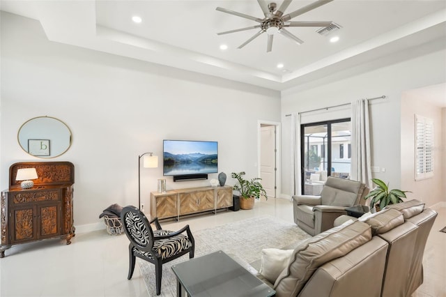 living area featuring recessed lighting, a tray ceiling, baseboards, and ceiling fan