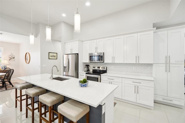 kitchen featuring decorative backsplash, a breakfast bar, a kitchen island with sink, stainless steel appliances, and a sink