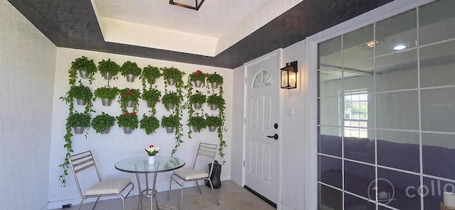 dining space featuring a textured ceiling, a textured wall, and a raised ceiling