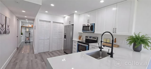 kitchen with light countertops, recessed lighting, appliances with stainless steel finishes, white cabinetry, and light wood-type flooring