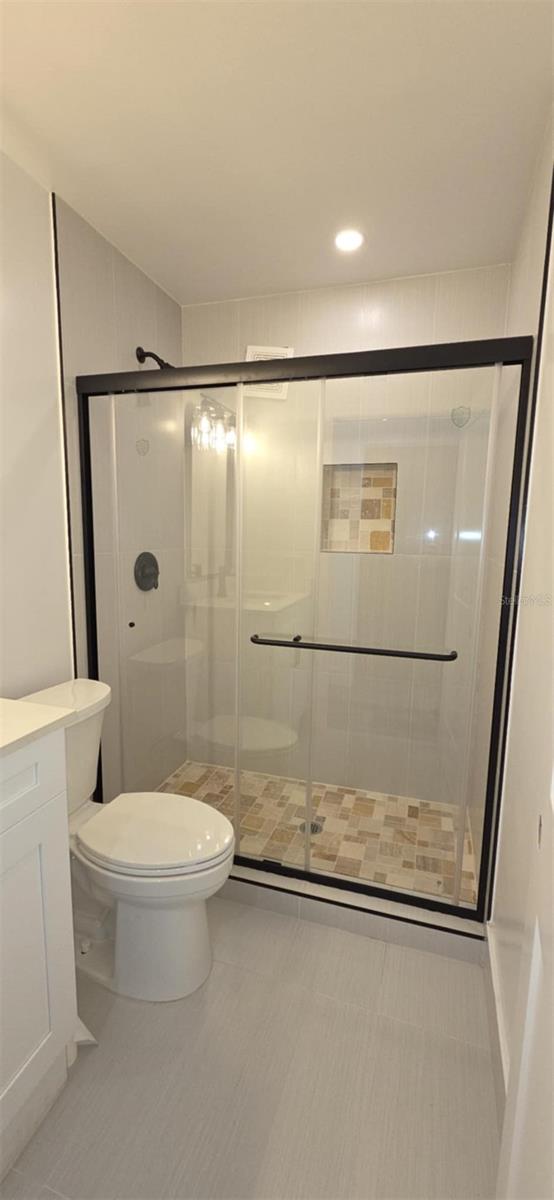 bathroom with a shower stall, toilet, and vanity