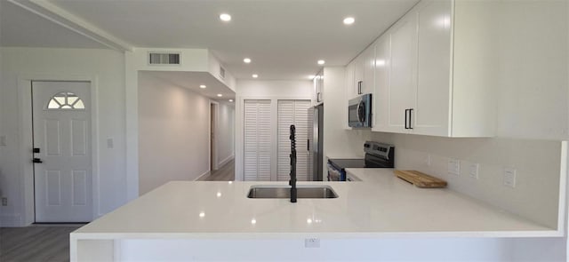 kitchen with visible vents, a peninsula, stainless steel appliances, recessed lighting, and white cabinetry