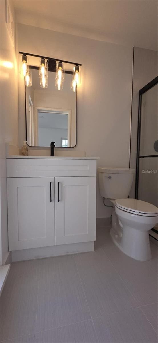 full bathroom with a shower with shower door, toilet, and vanity