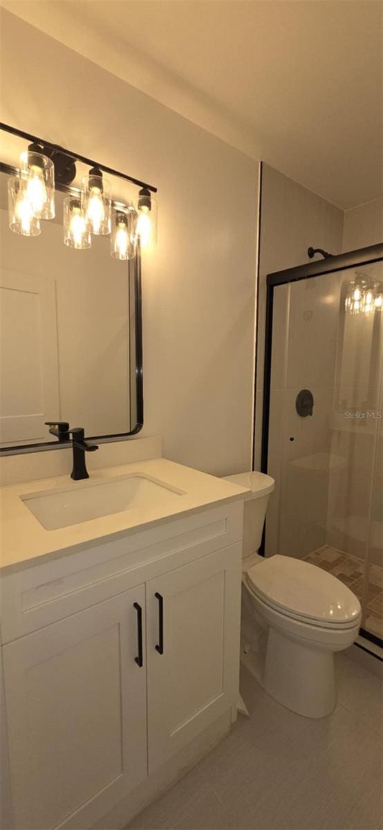 bathroom featuring toilet, vanity, and a stall shower