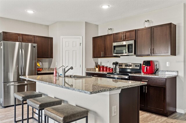 12856 French Market Dr, Riverview, FL 33579 - kitchen with dark brown cabinets, a kitchen bar, a sink, and stainless steel appliances