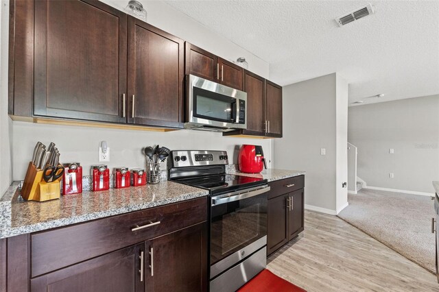 12856 French Market Dr, Riverview, FL 33579 - kitchen with stainless steel appliances, a textured ceiling, visible vents, light stone countertops, and dark brown cabinetry