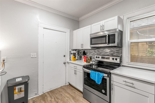 1134 9th Ave S, Saint Petersburg, FL 33705 - kitchen with tasteful backsplash, crown molding, stainless steel appliances, light wood-style floors, and white cabinets