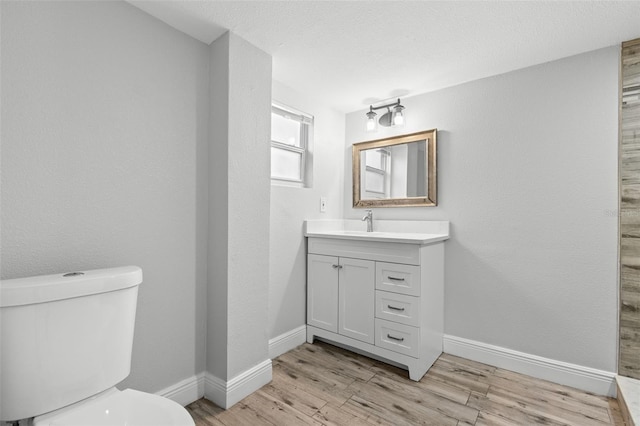 1134 9th Ave S, Saint Petersburg, FL 33705 - bathroom featuring toilet, vanity, wood finished floors, a textured ceiling, and baseboards