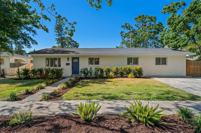 ranch-style house featuring a front yard, fence, and brick siding