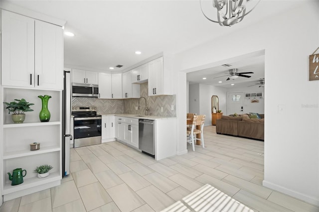 kitchen featuring tasteful backsplash, light countertops, white cabinets, and stainless steel appliances