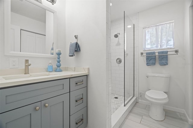full bath featuring toilet, tiled shower, vanity, and baseboards