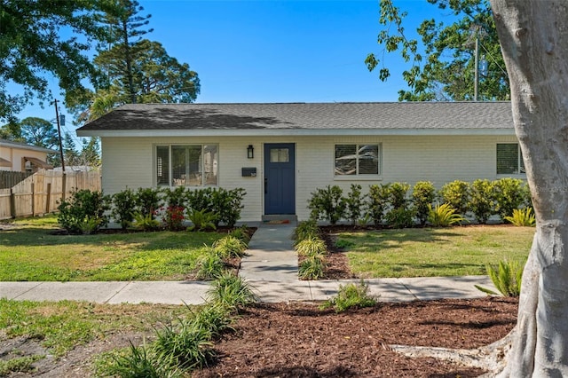 view of front of home featuring a front yard, fence, and brick siding