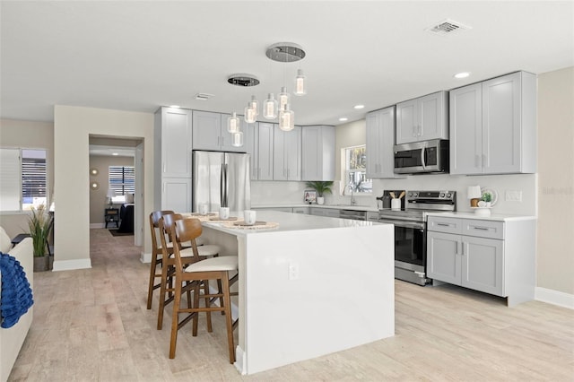 kitchen with light countertops, visible vents, a kitchen bar, appliances with stainless steel finishes, and a center island