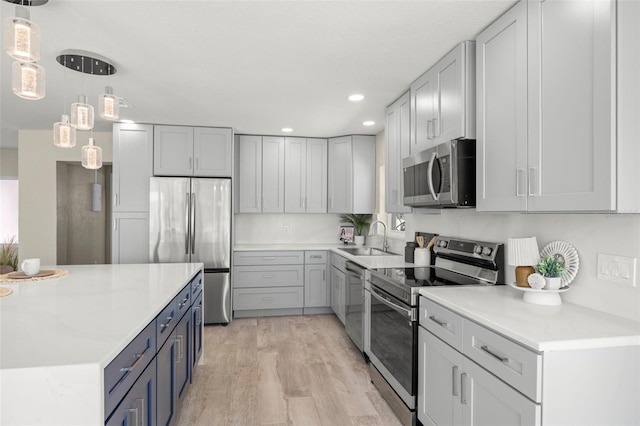 kitchen with light countertops, a sink, light wood-type flooring, and appliances with stainless steel finishes