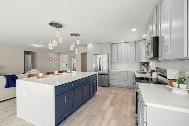 kitchen featuring open floor plan, light countertops, light wood-style flooring, and appliances with stainless steel finishes
