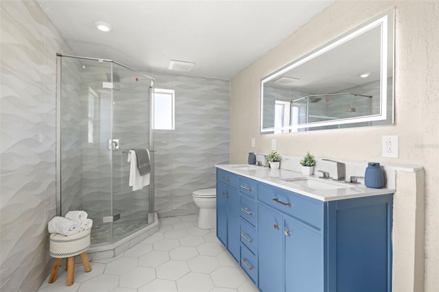 full bath featuring double vanity, a sink, and a shower stall