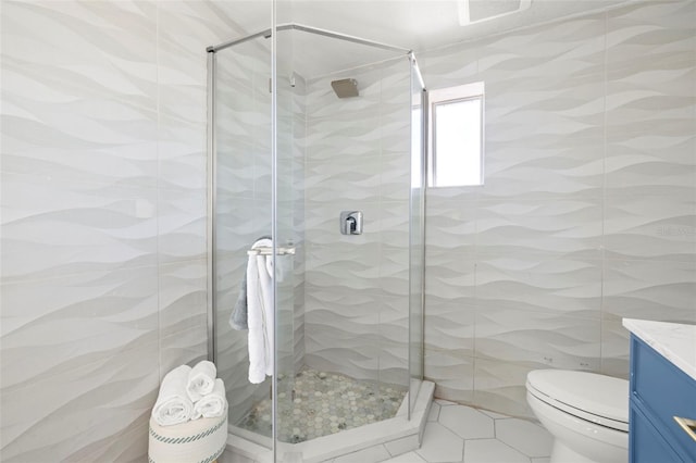 bathroom with toilet, vanity, tile walls, and a shower stall